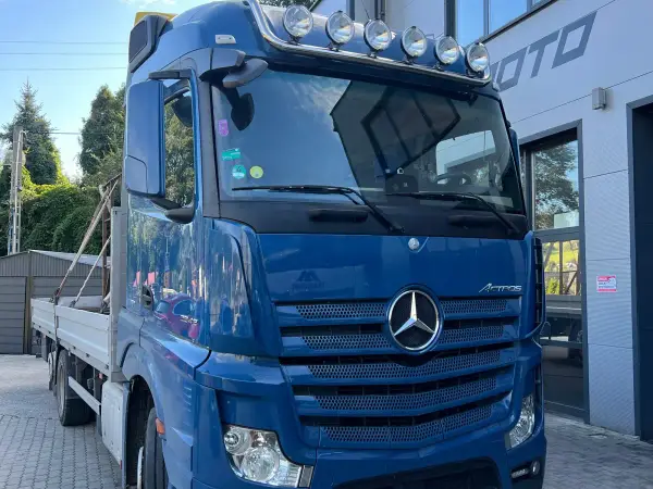 Niebieski Mercedes-Benz Actros ze skrzynią i żurawiem przed halą serwisową