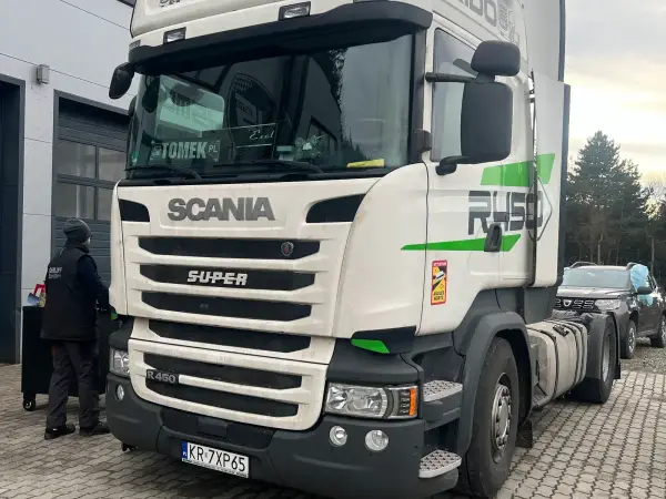 Biała Scania R450 w barwach firmy transportowej przed warsztatem w Tymbarku