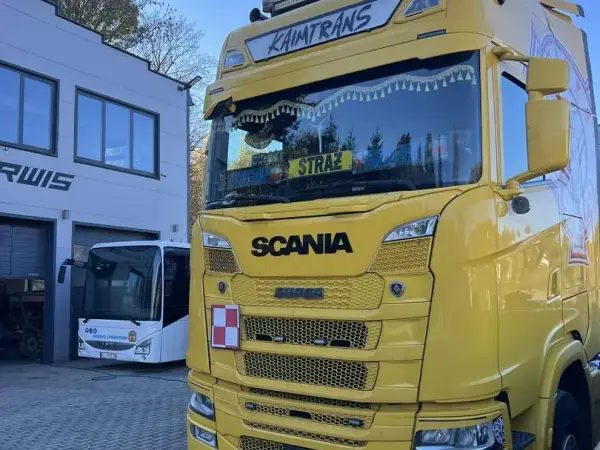 Żółta Scania nowej generacji i autobus miejski przed halą serwisową
