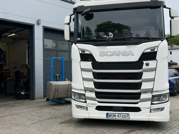 Biała Scania nowej generacji przed otwartą bramą warsztatową