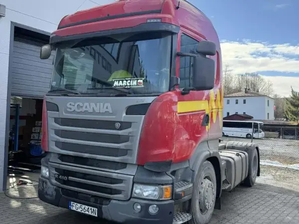 Czerwono-srebrna Scania R410 przed halą serwisową w słoneczny zimowy dzień