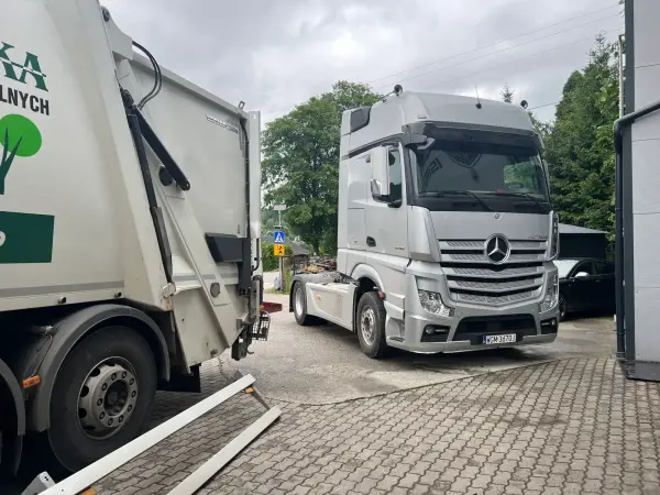 Srebrny Mercedes-Benz Actros obok śmieciarki przed serwisem regeneracji filtrów