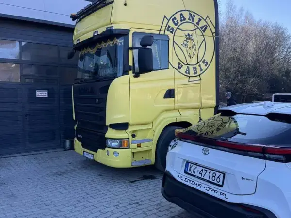 Żółta Scania Vabis przed bramą warsztatu, obok samochód osobowy serwisu